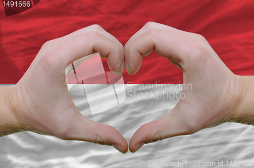 Image of Heart and love gesture showed by hands over flag of indonesia ba