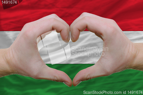 Image of Heart and love gesture showed by hands over flag of hungary back