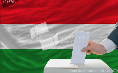 Image of man voting on elections in hungary in front of flag