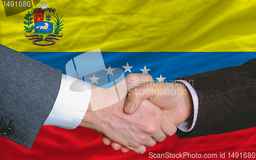 Image of businessmen handshake after good deal in front of venezuela flag