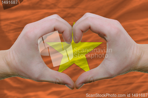 Image of Heart and love gesture showed by hands over flag of vietnam back