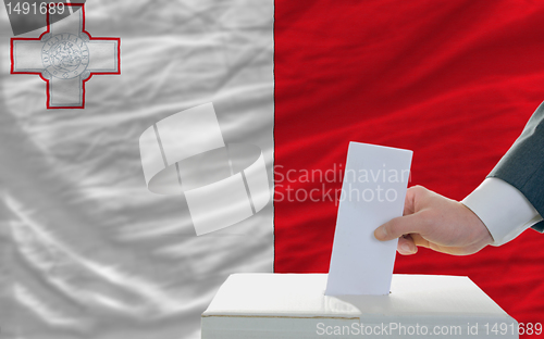 Image of man voting on elections in malta in front of flag