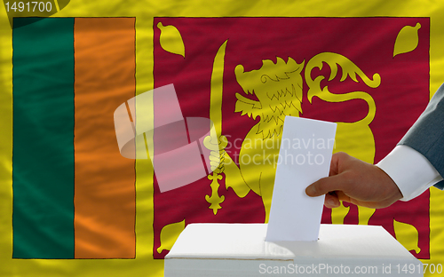 Image of man voting on elections in srilanka in front of flag