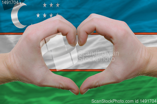 Image of Heart and love gesture showed by hands over flag of uzbekistan b