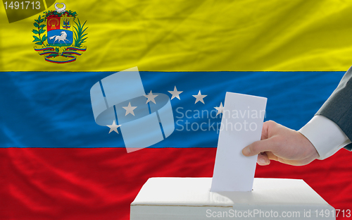 Image of man voting on elections in venezuela in front of flag