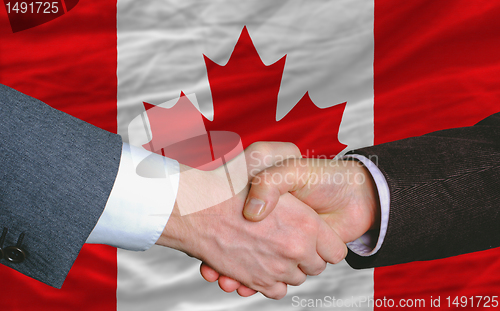Image of businessmen handshake after good deal in front of canada flag