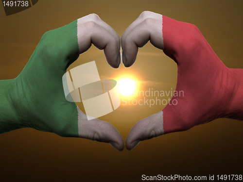 Image of Heart and love gesture by hands colored in italy flag during bea