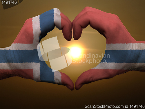 Image of Heart and love gesture by hands colored in norway flag during be