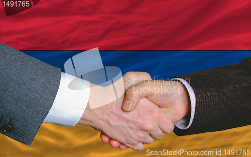Image of businessmen handshake after good deal in front of armenia flag