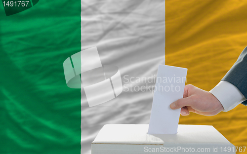 Image of man voting on elections in ireland in front of flag
