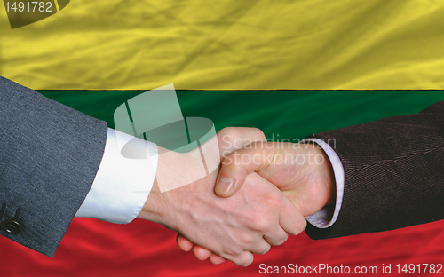 Image of businessmen handshake after good deal in front of lithuania flag