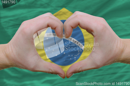 Image of Heart and love gesture showed by hands over flag of Brazil backg