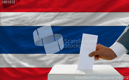 Image of man voting on elections in thailand in front of flag