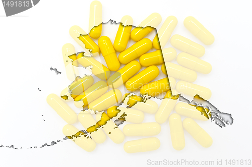 Image of Outline Alaska map of with transparent pills in the background
