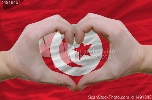 Image of Heart and love gesture showed by hands over flag of tunisia back