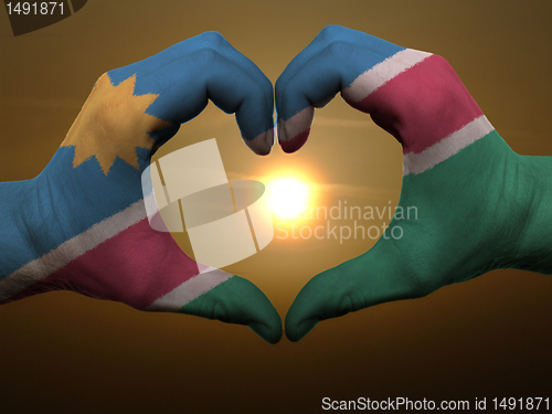 Image of Heart and love gesture by hands colored in namibia flag during b