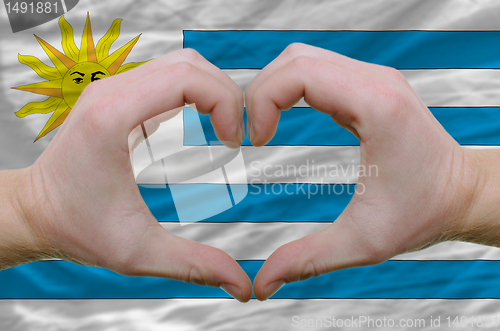 Image of Heart and love gesture showed by hands over flag of uruguay back