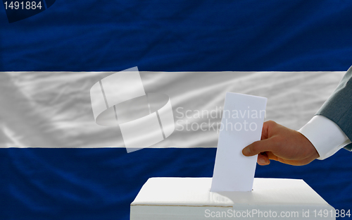 Image of man voting on elections in nicaragua in front of flag