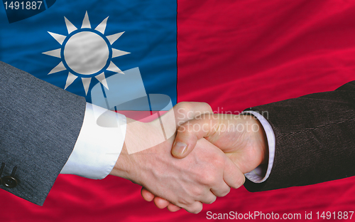 Image of businessmen handshake after good deal in front of taiwan flag