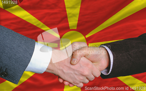 Image of businessmen handshake after good deal in front of macedonia flag