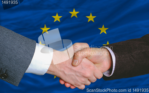 Image of businessmen handshake after good deal in front of europe flag