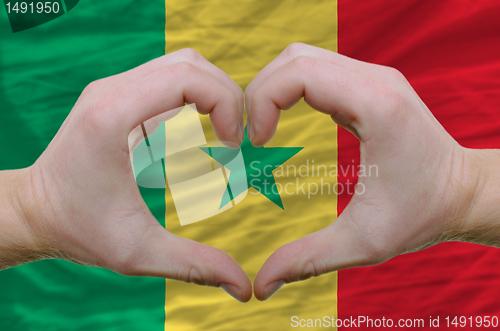 Image of Heart and love gesture showed by hands over flag of senegal back