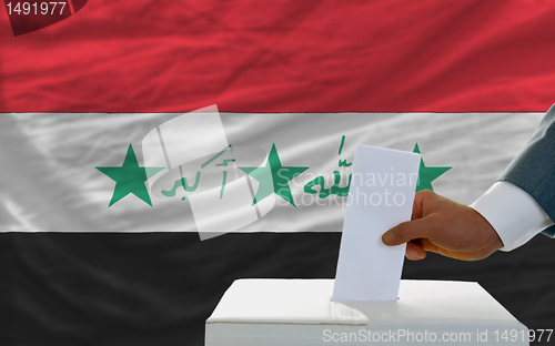 Image of man voting on elections in iraq in front of flag