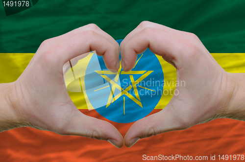 Image of Heart and love gesture showed by hands over flag of ethiopia bac