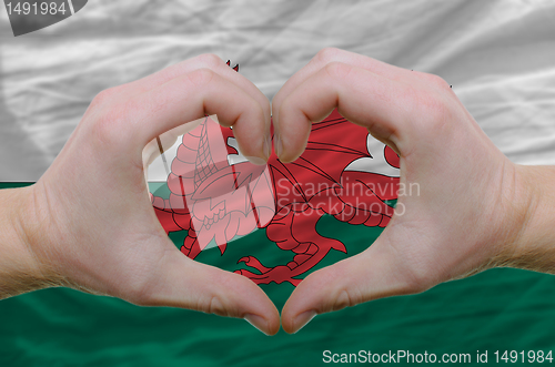 Image of Heart and love gesture showed by hands over flag of wales backgr