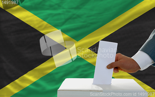 Image of man voting on elections in jamaica in front of flag