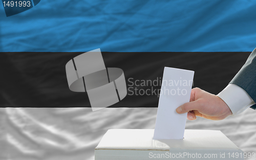 Image of man voting on elections in estonia in front of flag