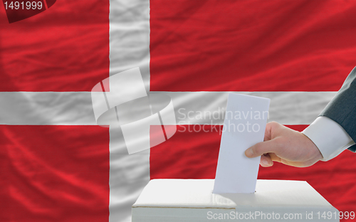 Image of man voting on elections in denmark in front of flag