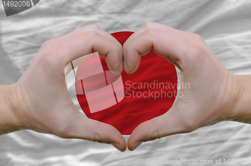 Image of Heart and love gesture showed by hands over flag of japan backgr