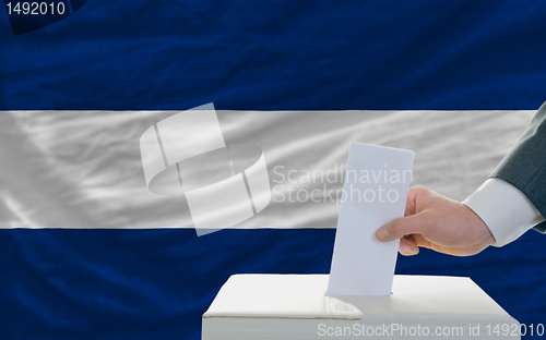 Image of man voting on elections in nicaragua in front of flag