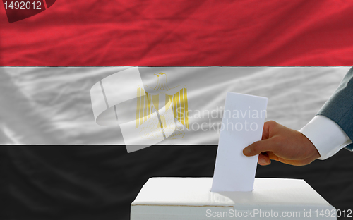 Image of man voting on elections in egypt in front of flag