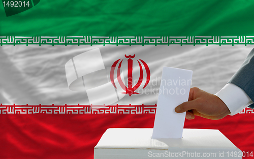 Image of man voting on elections in iran in front of flag