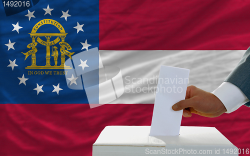 Image of man voting on elections in georgia in front of flag