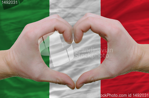 Image of Heart and love gesture showed by hands over flag of italy backgr