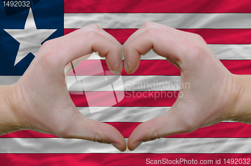 Image of Heart and love gesture showed by hands over flag of liberia back