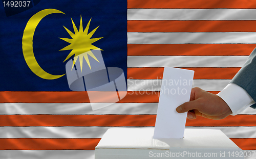 Image of man voting on elections in malaysia in front of flag