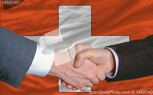 Image of businessmen handshake after good deal in front of swiss flag