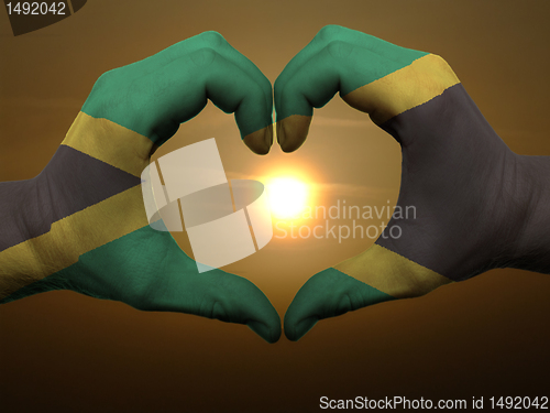 Image of Heart and love gesture by hands colored in jamaica flag during b