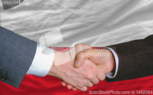 Image of businessmen handshake after good deal in front of poland flag