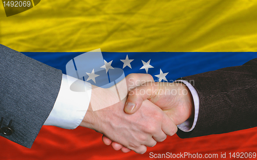 Image of businessmen handshake after good deal in front of venezuela flag