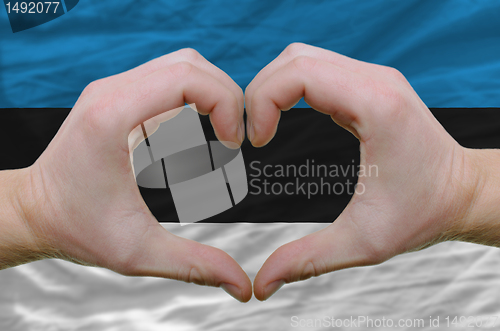 Image of Heart and love gesture showed by hands over flag of estonia back
