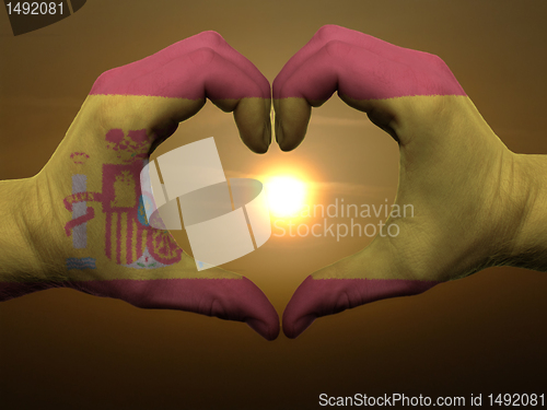 Image of Heart and love gesture by hands colored in spain flag during bea