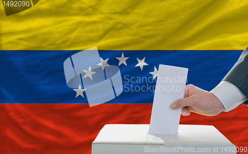 Image of man voting on elections in venezuela in front of flag