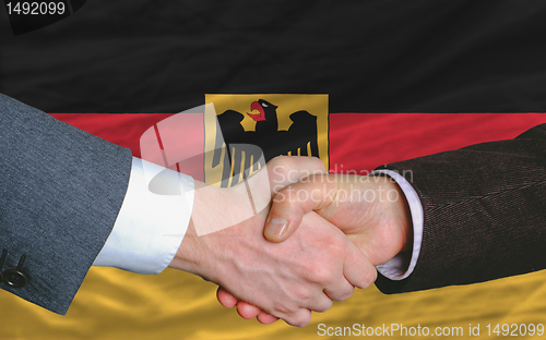 Image of businessmen handshake after good deal in front of germany flag