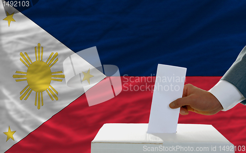 Image of man voting on elections in phillipines in front of flag