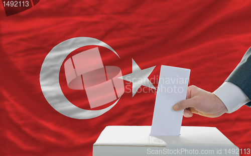 Image of man voting on elections in turkey in front of flag